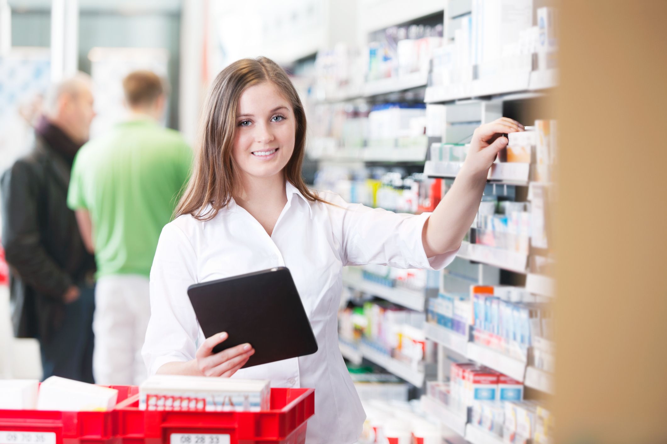 Female pharmacist holding a tablet and reaching for medicine Medication Management