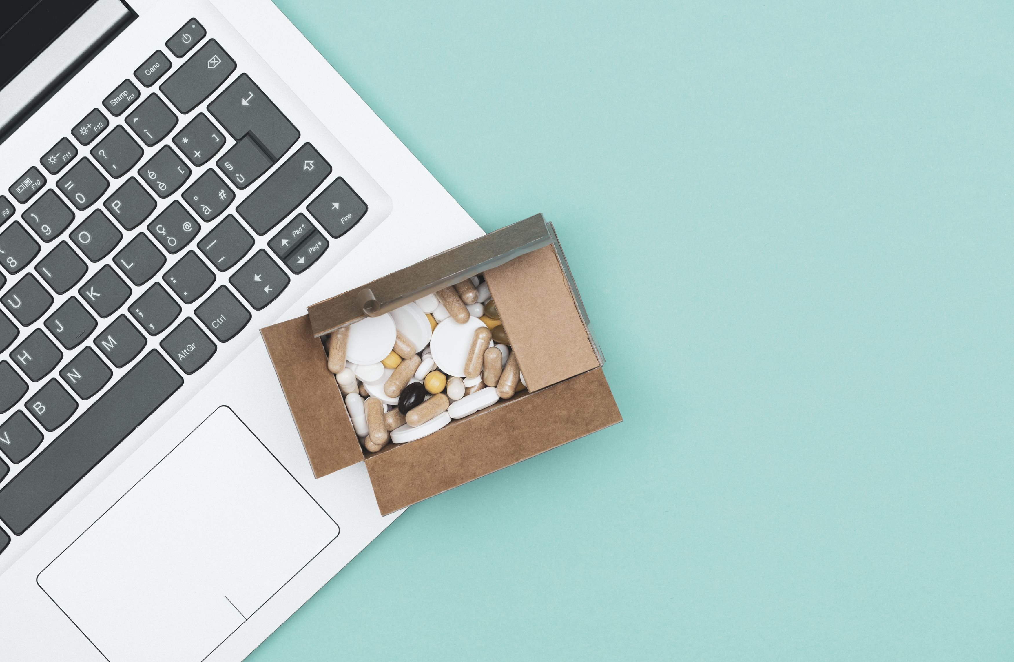 Box of pills sitting on top of a laptop. Delivery
