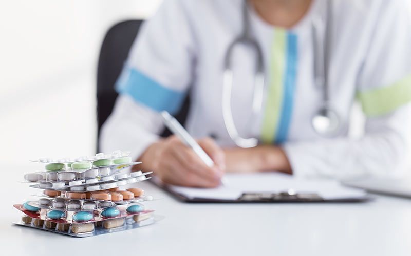 Pharmacist listing stacks of medications