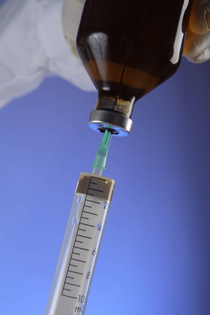 Syringe drawing liquid medication from a vial. Syringe drawing liquid medication from a vial.