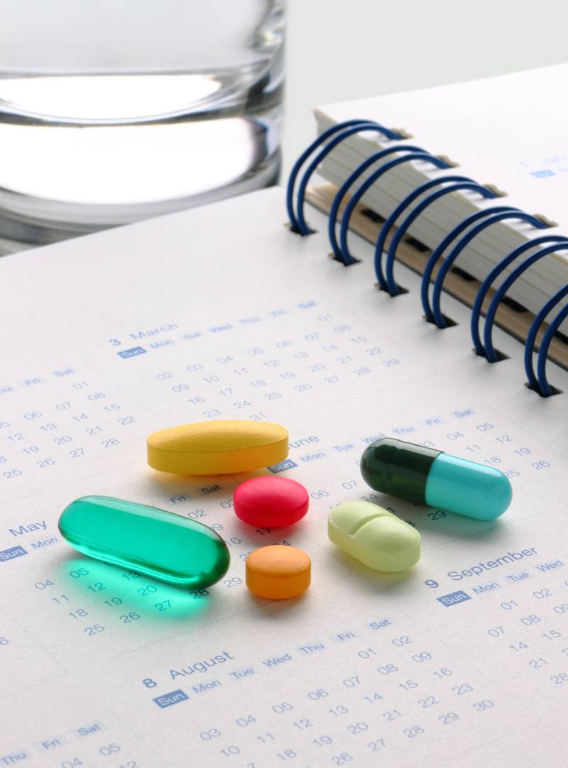 Variety of pills on top of a calendar book Variety of pills on top of a calendar book
