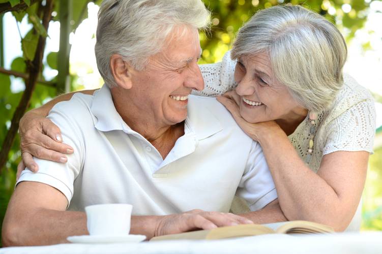 Elderly Couple Outside reading at table Elderly Couple Outside reading at table