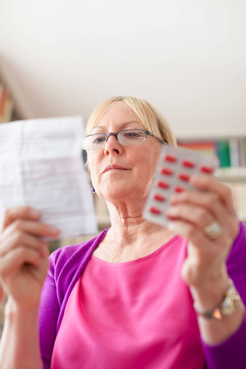 Woman holding a pack of medication reading the instructions Woman holding a pack of medication reading the instructions
