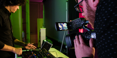 A videographer shooting a close-up of a DJ at a gala 