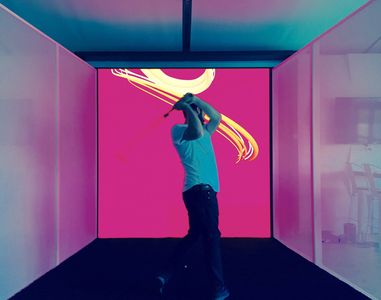 A U.S. Open attendee swinging a golf club at an LED video wall display