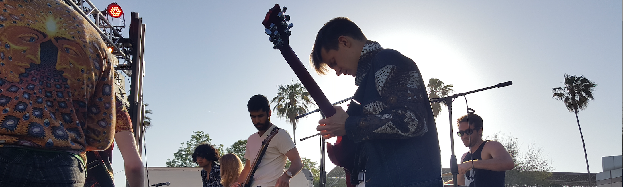 A guitarist performing on an electric guitar at an outdoor concert