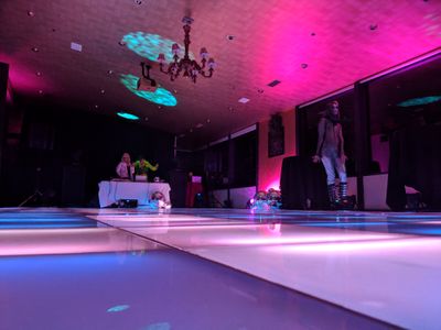 An image of a party with a lit-up dance floor and pink lighting 