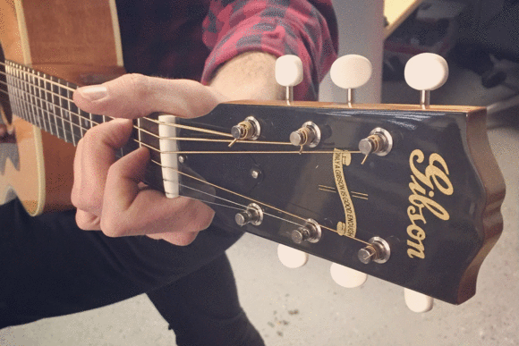 A man playing a Gibson acoustic guitar