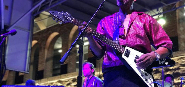 A man playing the electric guitar on stage at an outdoor concert