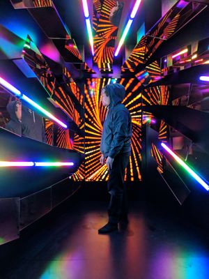 An event attendee posing for a photo in front of an LED display and neon lights