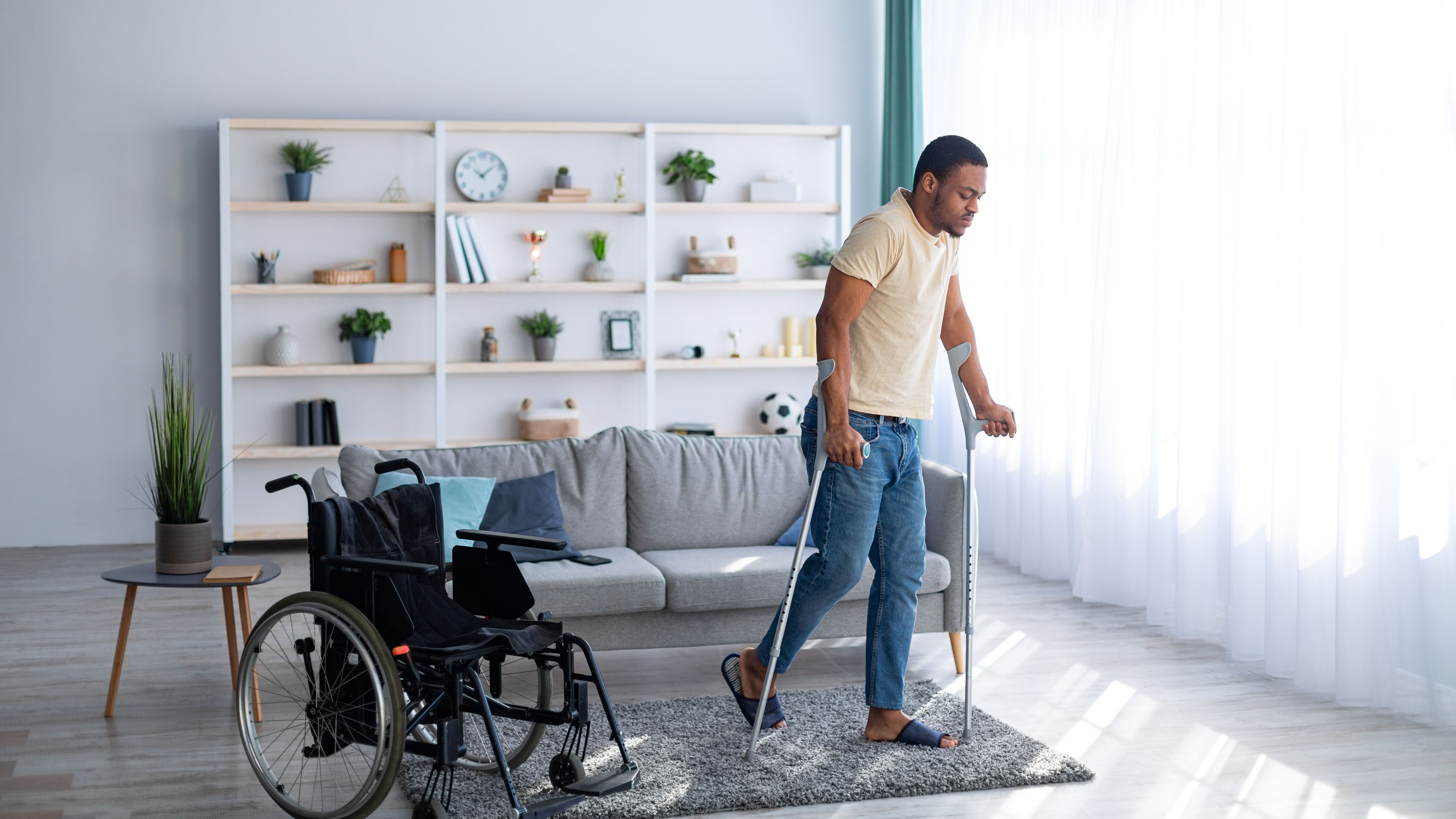 Image of a man walking with crutches and a wheelchair Durable Medical Equipment