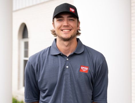 GPRS Project Manager Colton Carney, a young man in a grey GPRS polo shirt and a black GPRS hat. He is smiling at the camera. GPRS Project Manager Colton Carney is an expert in reality capture, utilizing 3D LiDAR laser scanners and photogrammetry equipment to provide highly accurate interior and exterior measurements.