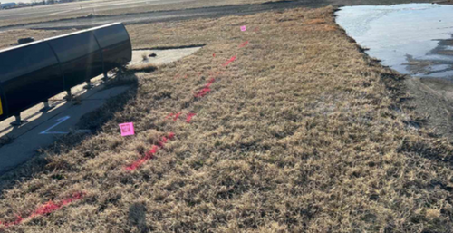 GPRS flags and markings alongside the airport taxiway, delineating a utility line.