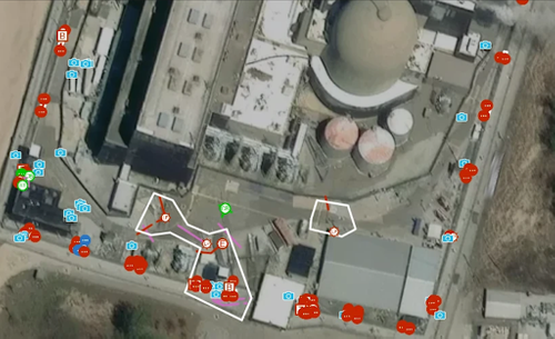 A satellite image of a small portion of a nuclear facility overlaid with digital utility map details inside SiteMap. Areas of red, green, blue, and pink, plus icons indicating field photos and annotations can be seen, as well as two work areas outlined in white. Detail shot of the scope of work.png