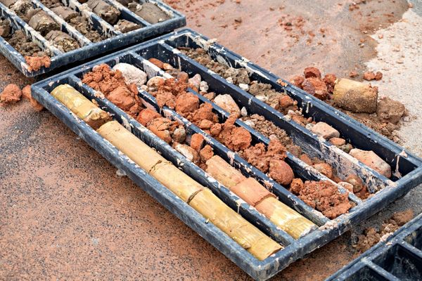A plastic rack containing several kinds of soil core samples, including clay, and rock. Soil boring samples and testing are a key component of Phase II ESAs. Obtaining Soil boring clearances ensures that no subsurface utilities will be struck during sampling.