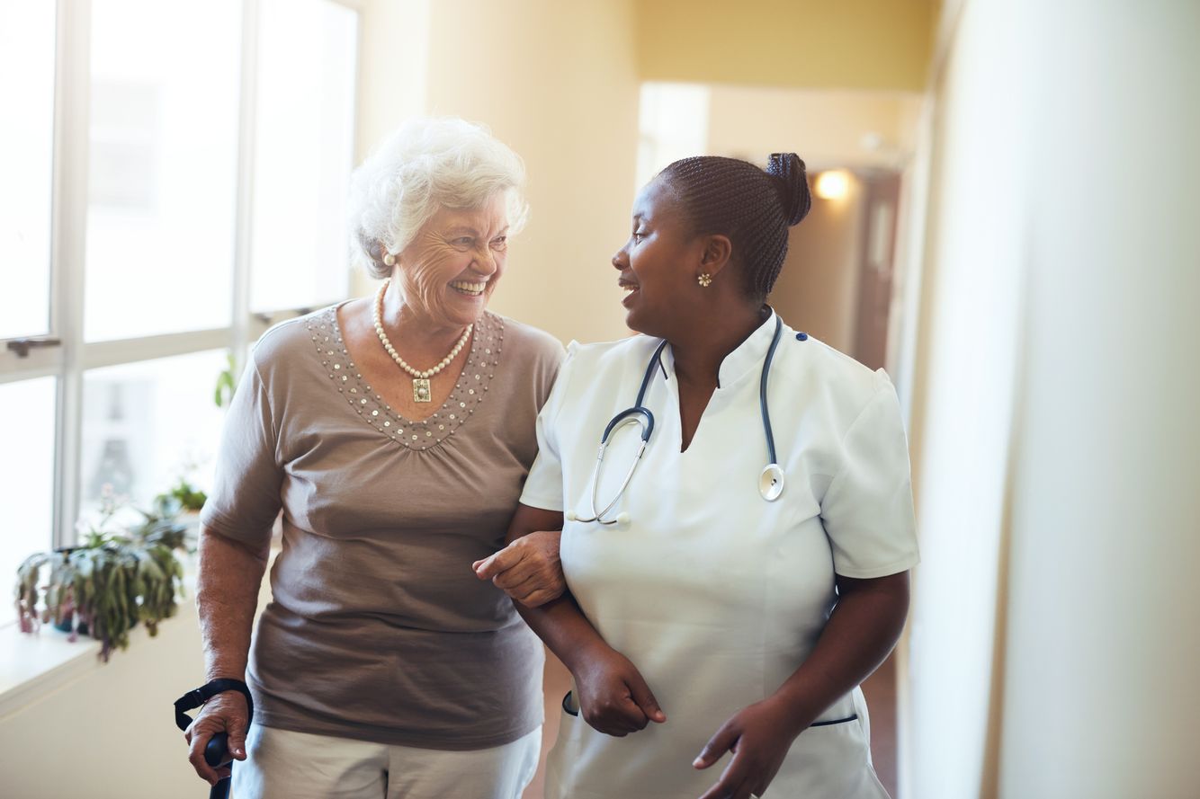 Image of an elderly woman walking with healthcare professional Long Term Care