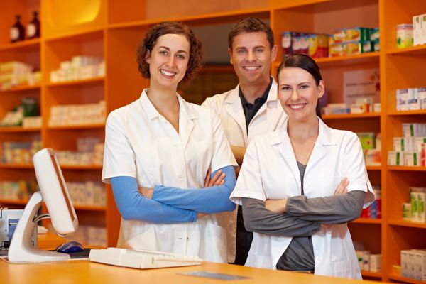 Image of three pharmacist behind a pharmacy counter smiling About Us