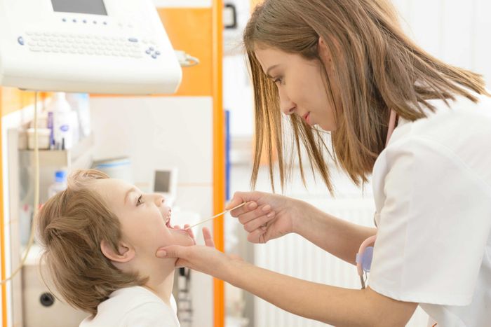 A pharmacist tests a child for strep Flu and strep testing
