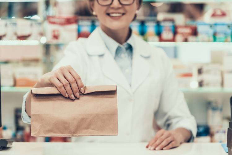 Woman handing over medication in a paper bag. MTM