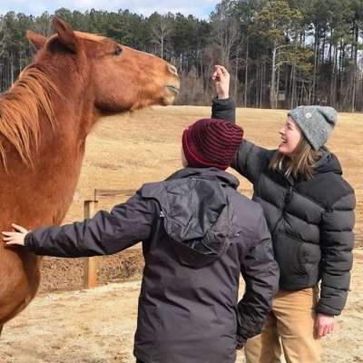 A young adult engaging in equine therapy with a therapist nearby, illustrating experiential treatment options for borderline personality disorder. Equine Therapy for Borderline Personality Disorder