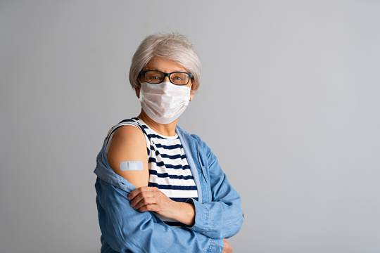 Older woman with a bandaid on her upper arm Immunizations