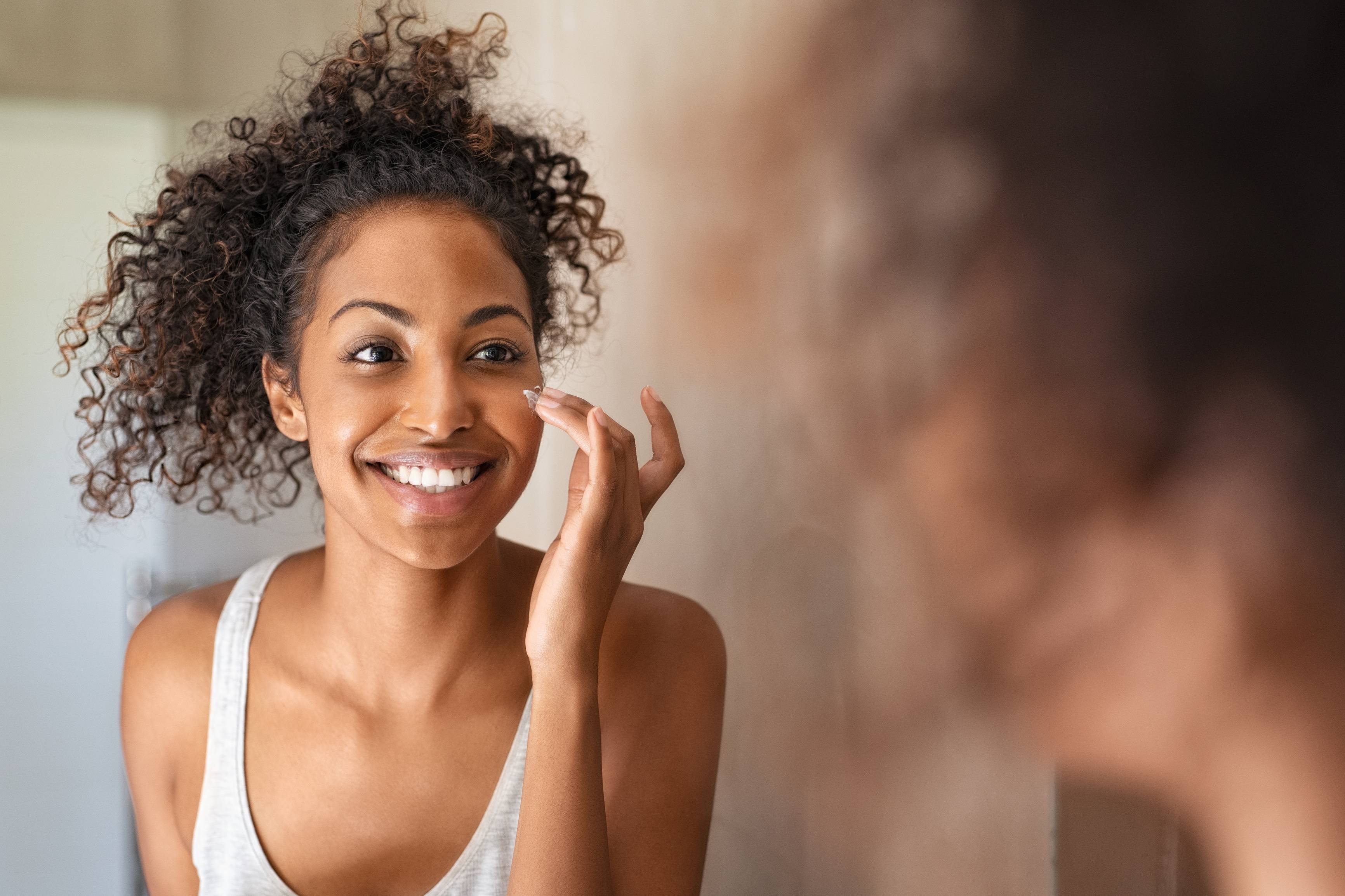 Woman looking at her skin in the mirror Dermatology