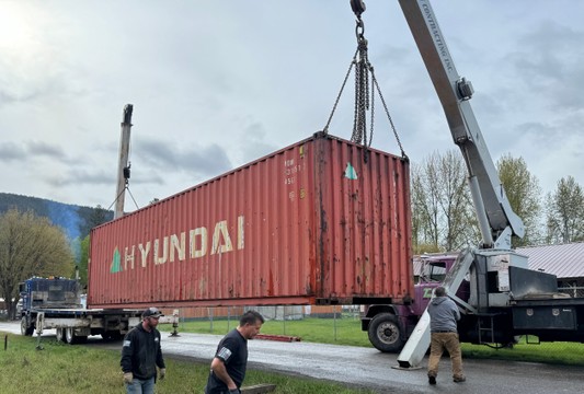 crane lifting red shipping container