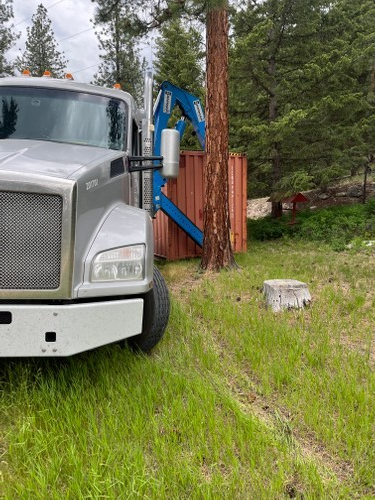 sideloader truck moving container next to tree