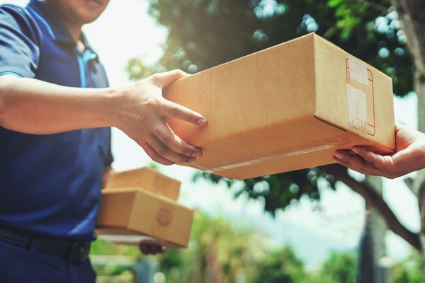 Image of delivery guy handing out package. Delivery