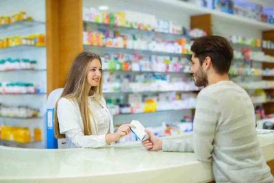 Customer checking medication with pharmacist at counter
