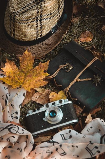 free-photo-of-printed-scarf-closed-leather-diary-and-straw-hat-on-grass-with-autumnal-leaves.jpeg
