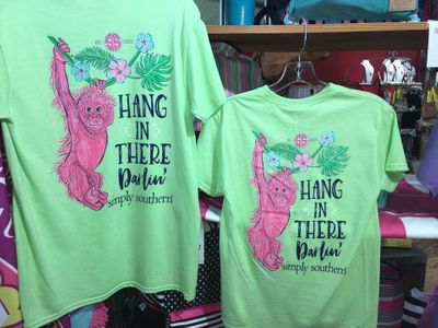 Two lime green t-shirts with the words hang in there darlin' on the back Harvest Drug and Gift shop items
