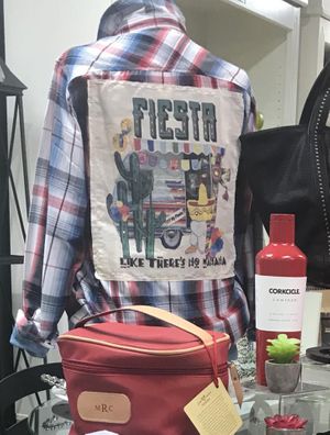 Mannequin waring a plaid long sleeve shirt with the words fiesta on the back Harvest Drug and Gift shop items