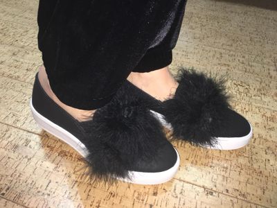 Woman wearing black slip on sneakers with black fuzzy balls on top Harvest Drug and Gift shop items