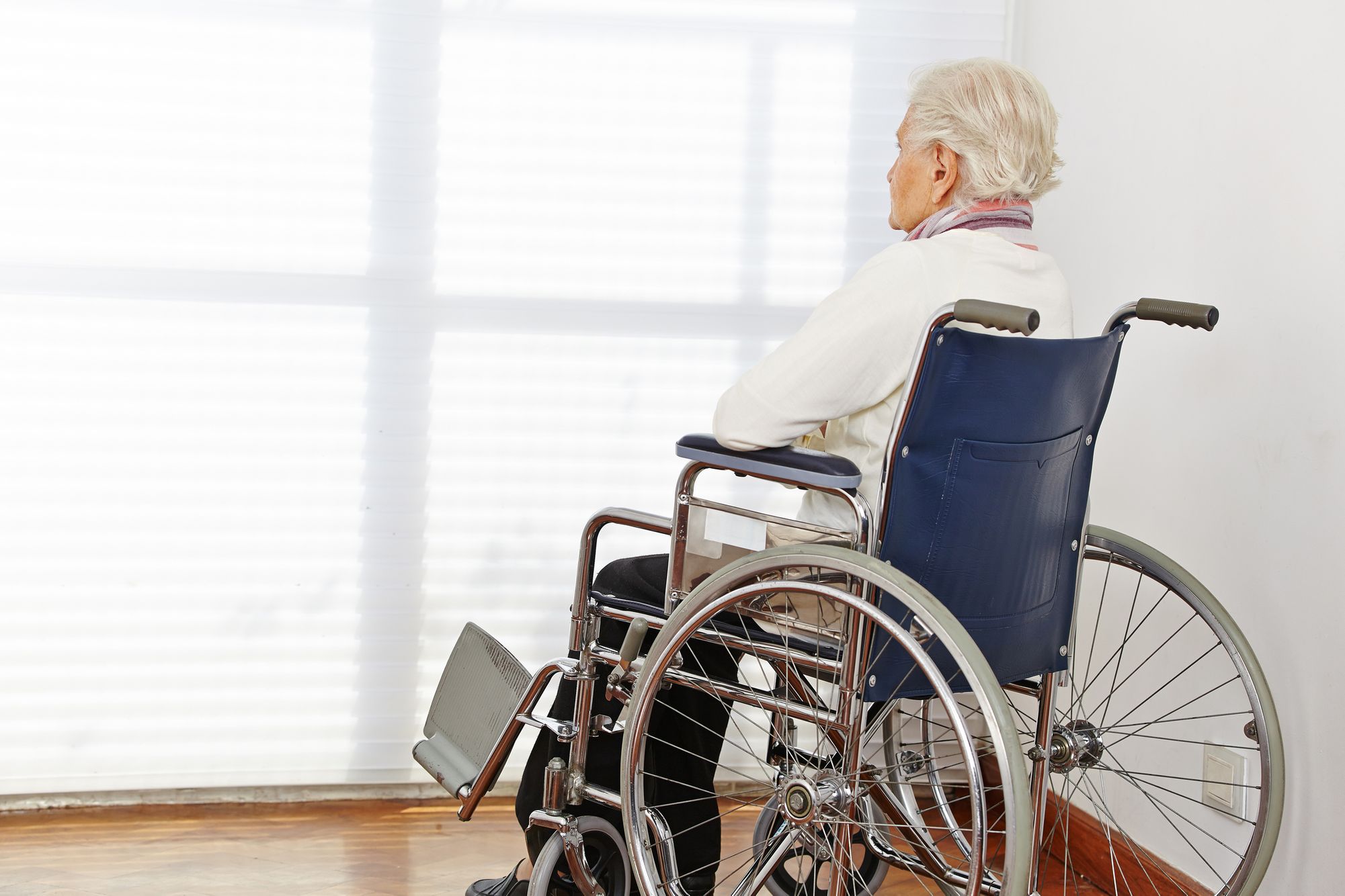 Elderly person sitting in a wheelchair near a bright window, symbolizing long-term care and mobility support. Senior in Wheelchair by Window