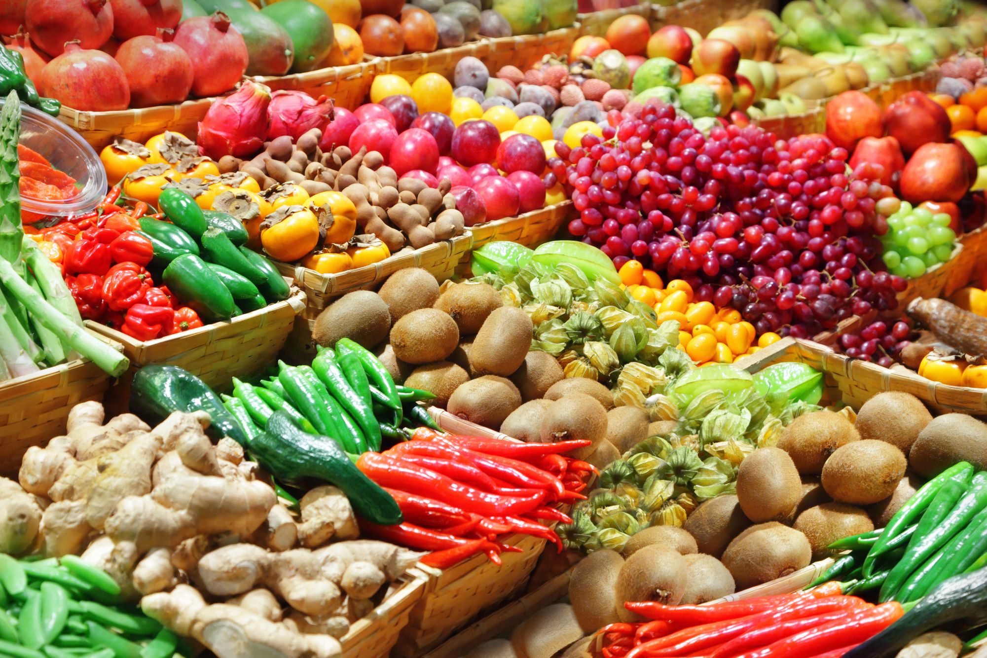 A colorful assortment of fresh vegetables including peppers, potatoes, and greens arranged on a market stand. Fresh Produce Display