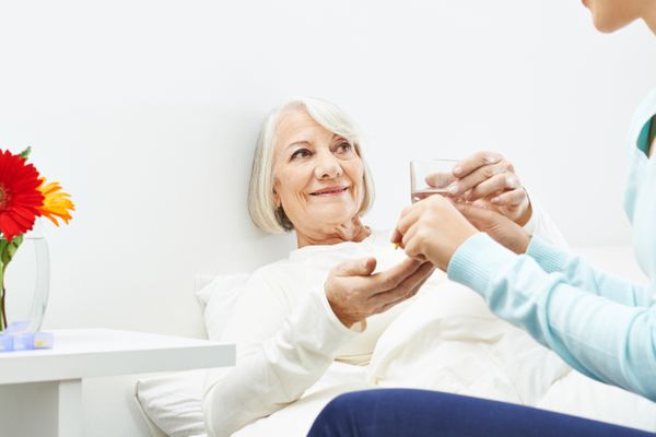 Senior woman taking pills with a glass of water