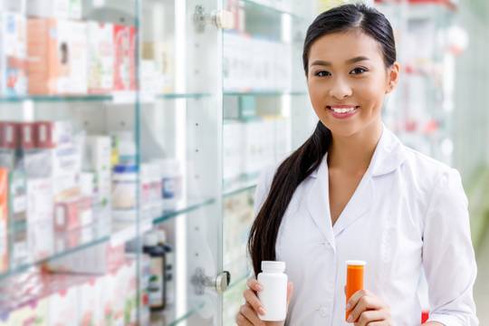 Image of pharmacist smiling and holding pills
