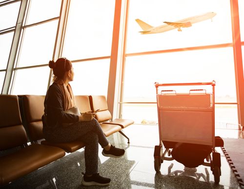 a person looks out at a plane taking off Travel Vaccinations