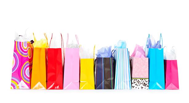 Row of colorful paper gift bags with tissue paper in various patterns and bright colors.