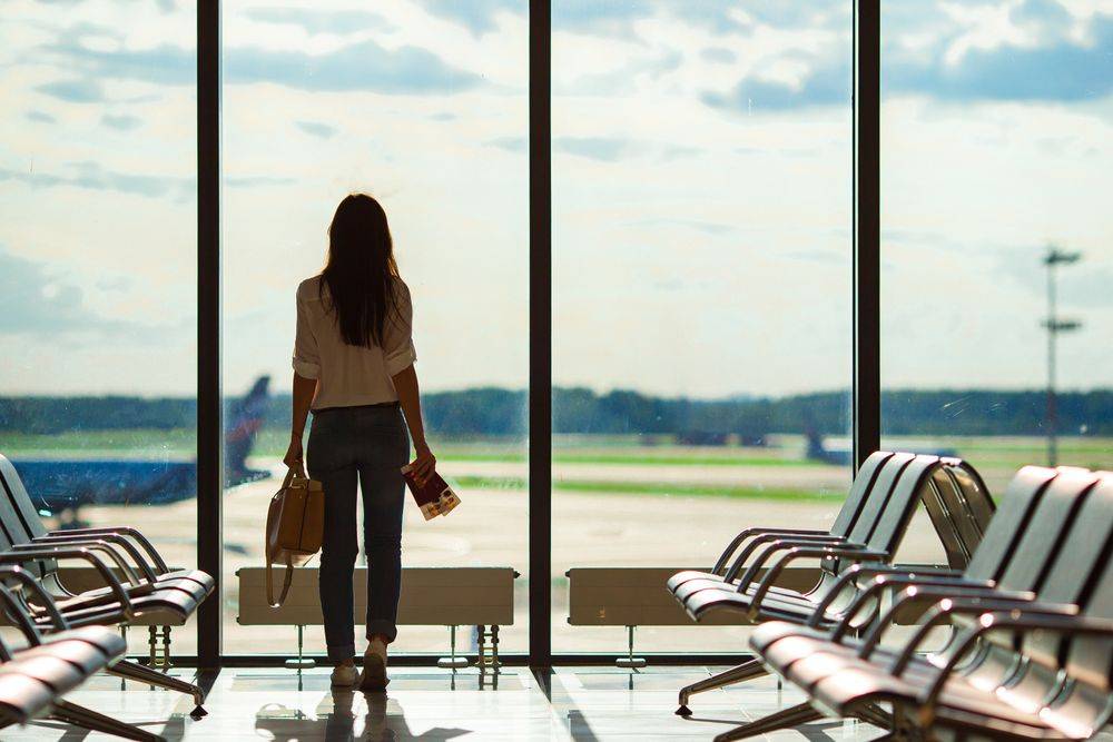 Image of a woman looking out from airport terminal Travel Vaccinations