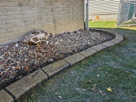 Decorative stone landscape border with river rock beside house