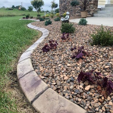 Curved stone landscape border with river rock and small plants