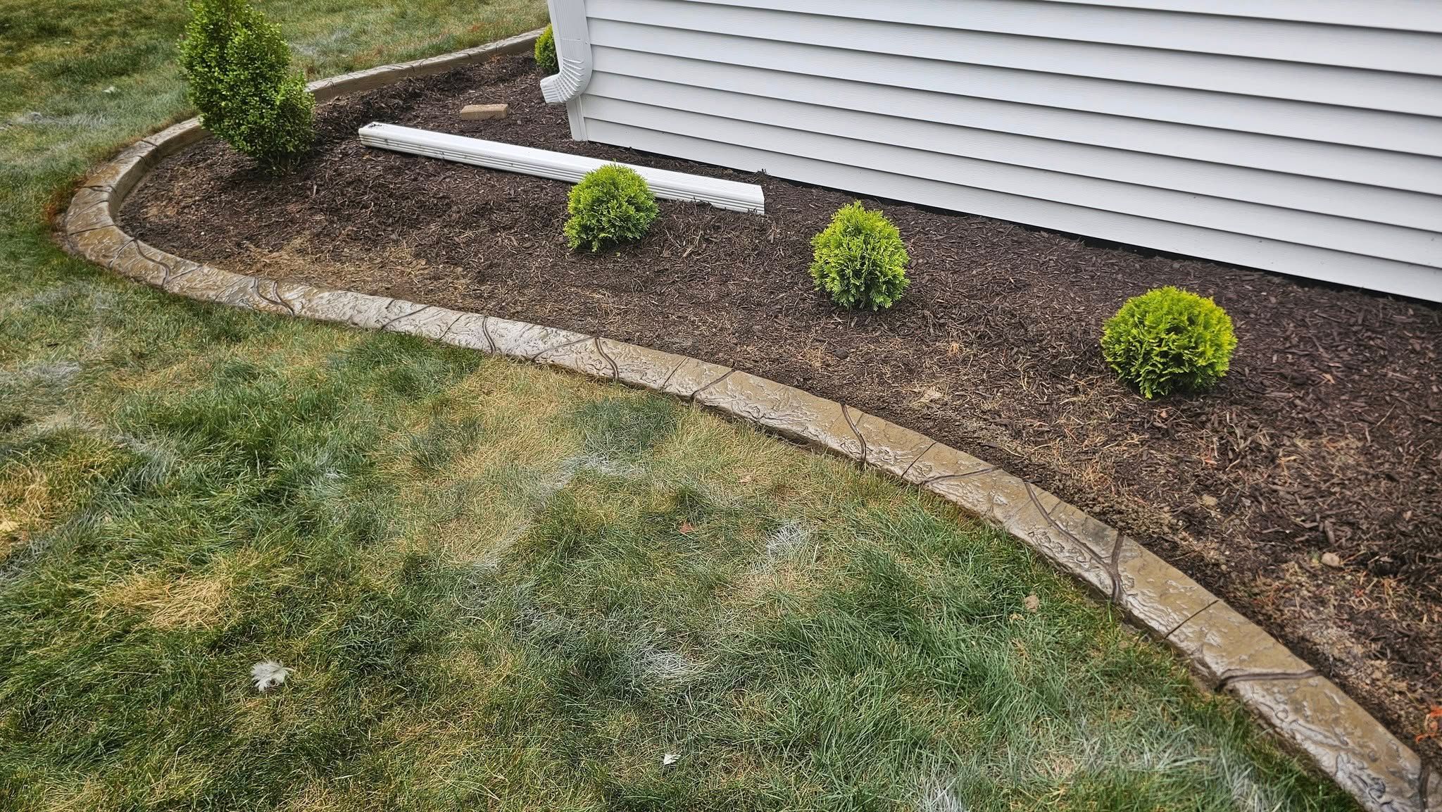 Curved Stamped Concrete Landscape Edging Along Home Foundation