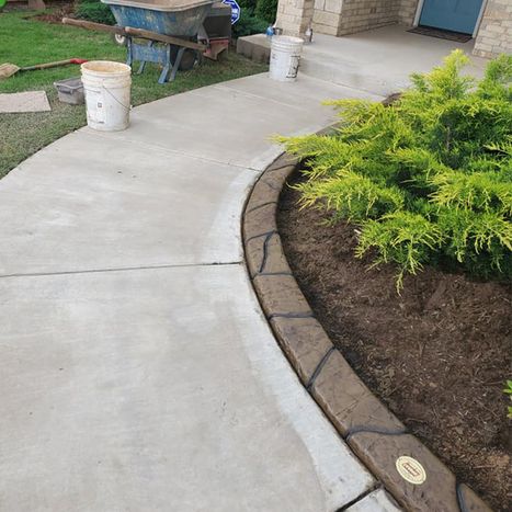 Decorative concrete landscape border beside curved sidewalk