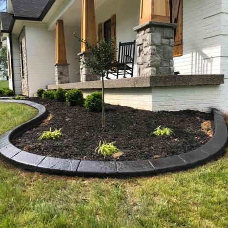Curved black stone landscape border with fresh mulch and small plants