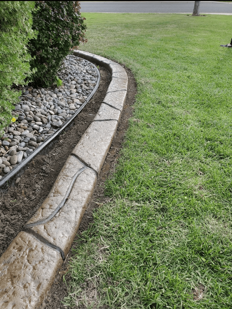 Concrete landscape Border edging between grass and river rock bed