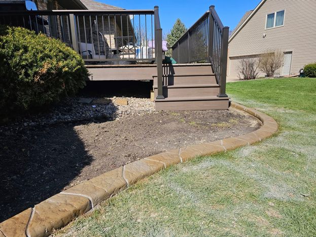 Decorative curved landscape border defining deck garden bed