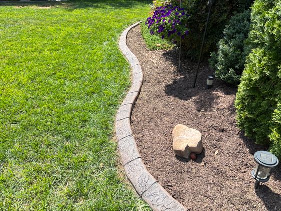 Decorative curved stone landscape border with mulch and flowers by Angelopulos StoneCraft