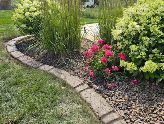 Curved stone landscape border with flowers, grasses, and decorative stone